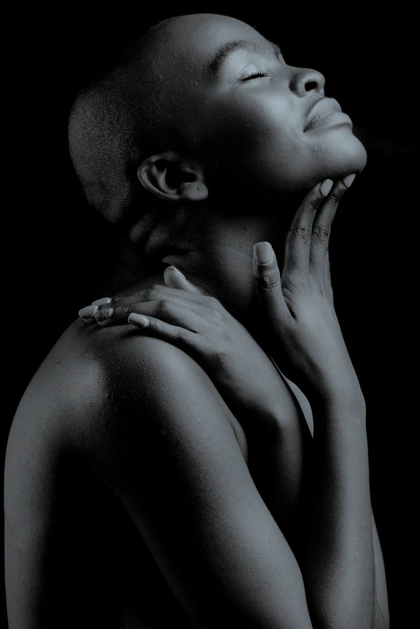 A person with eyes closed and a hand resting at their face, suggesting a quiet moment of attention and sensation.
