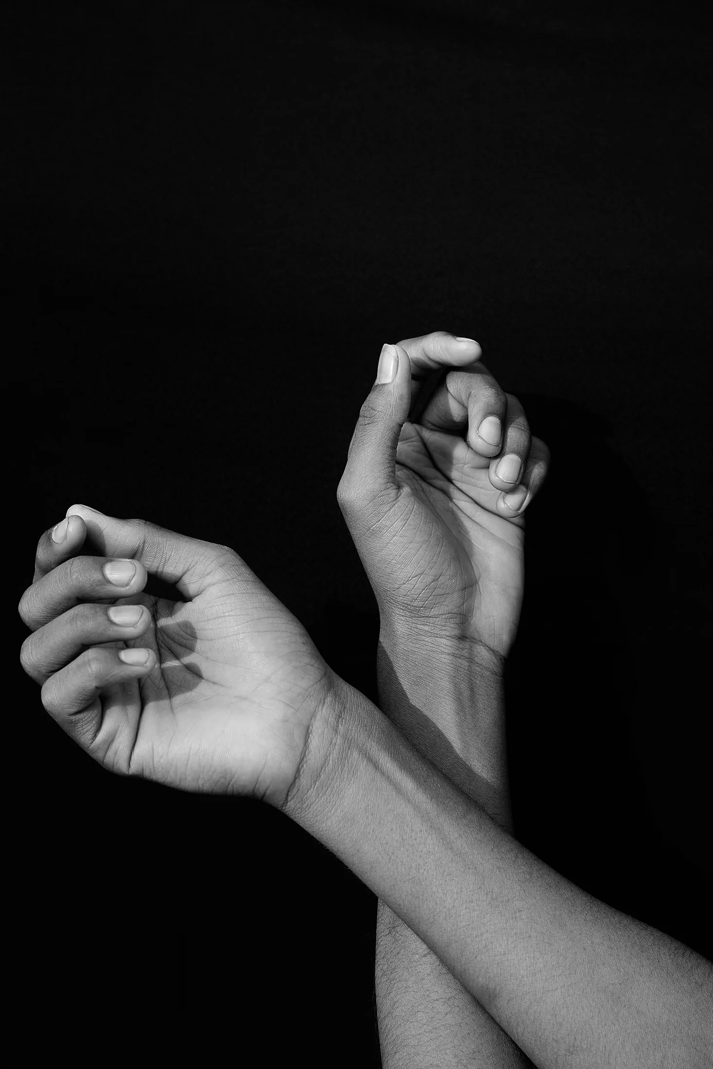 Hands held in a gentle gesture against a dark background, illustrating mindful touch and body awareness.