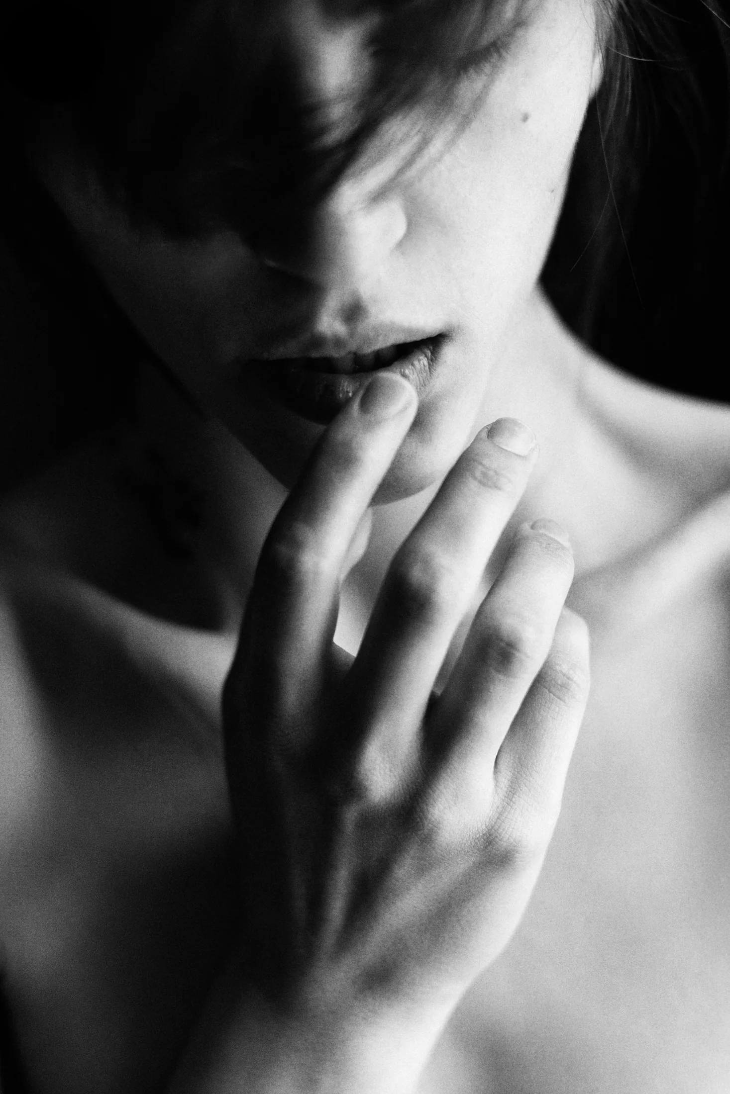 Black-and-white close-up of a person touching their lips, illustrating attention to sensation and sexual mindfulness.